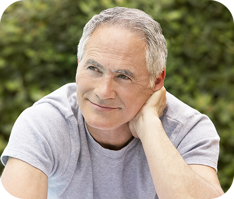 older man sitting outside with his right hand resting against his neck
