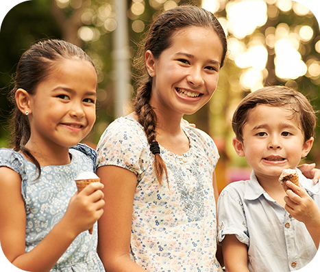 three siblings eating ice cream cones at the park