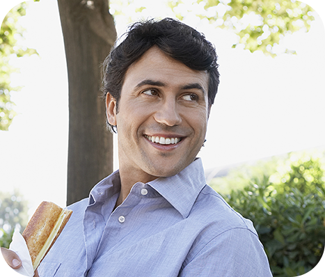 man enjoying a snack on a park bench before work